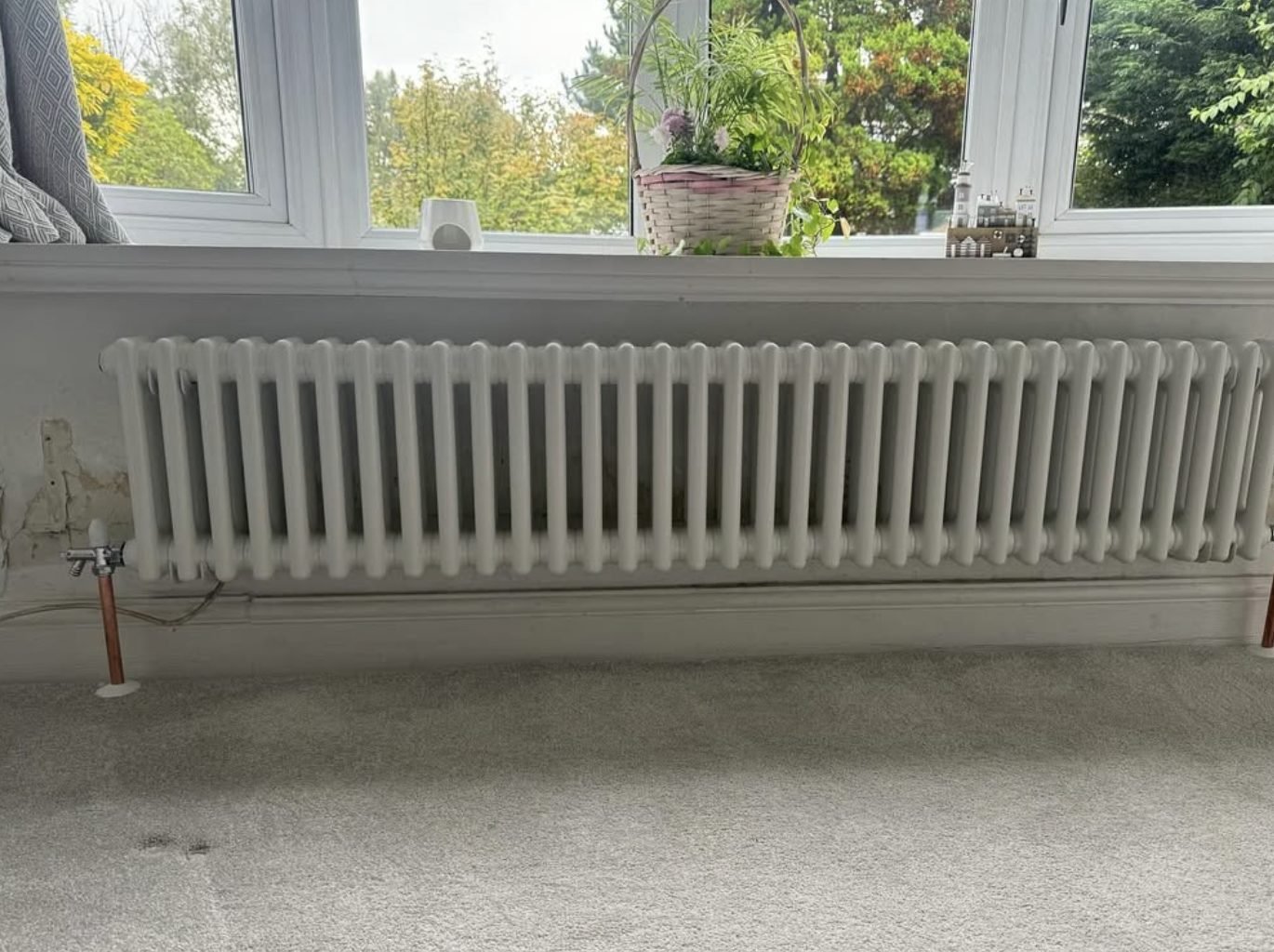 White column radiator fitted under a window