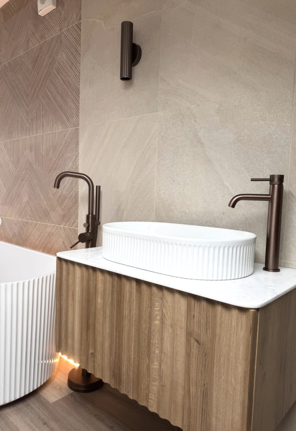 Fluted white vessel basin on an oak vanity with marble top and bronze taps